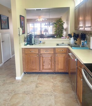 A kitchen with wooden cabinets, a coffee maker, a sink, and a plant. - Few minutes walk  to beach and pool. Few-minutes drive to historic district. (St. Augustine)