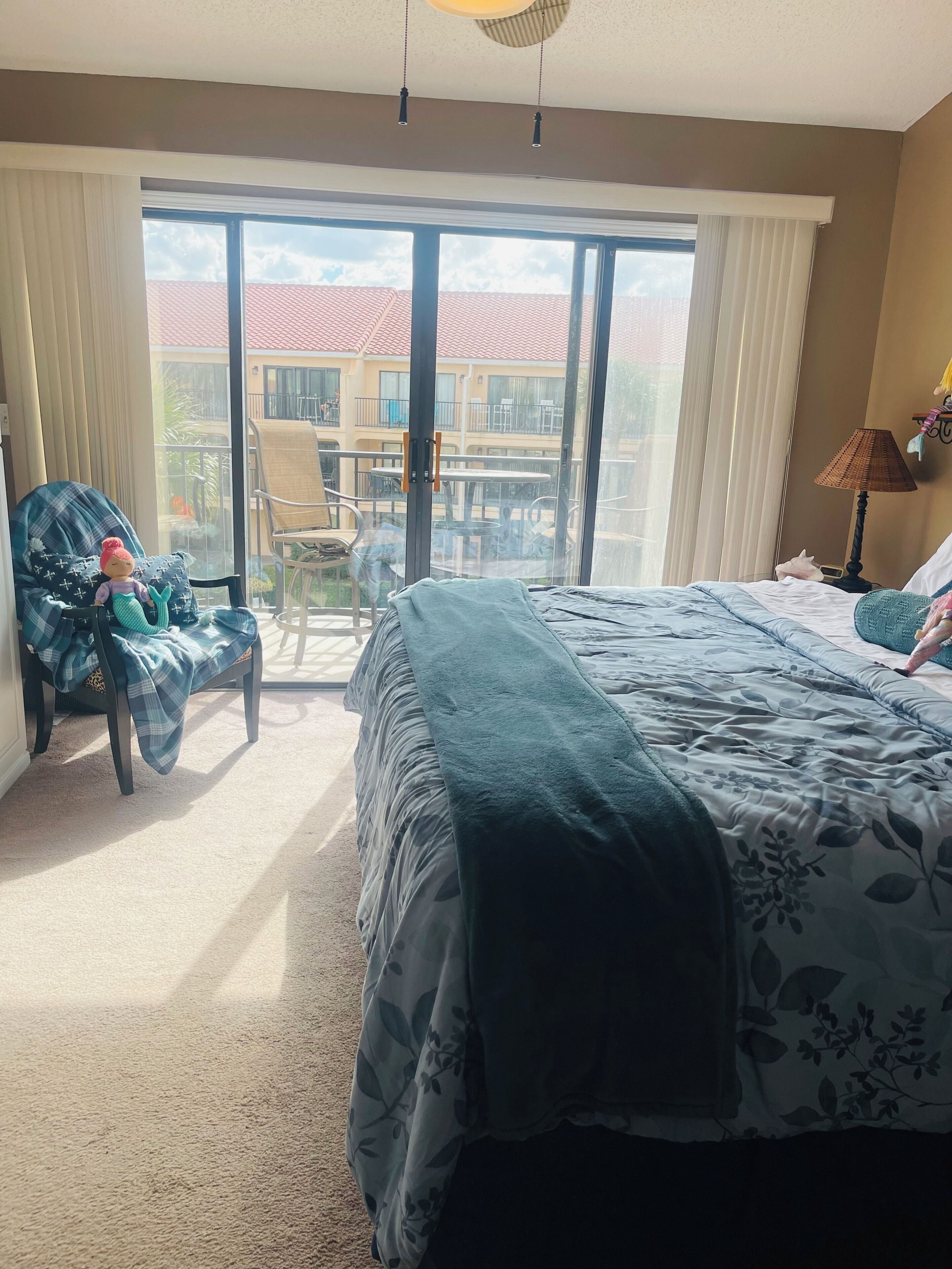 Ein Hotelzimmer mit einem großen Bett, einem Sessel, einem kleinen Tisch und Blick auf den Außenbalkon.