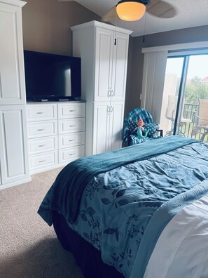 Una camera da letto con un letto grande, una televisione su un mobile e vista sull'esterno tramite una porta scorrevole.
