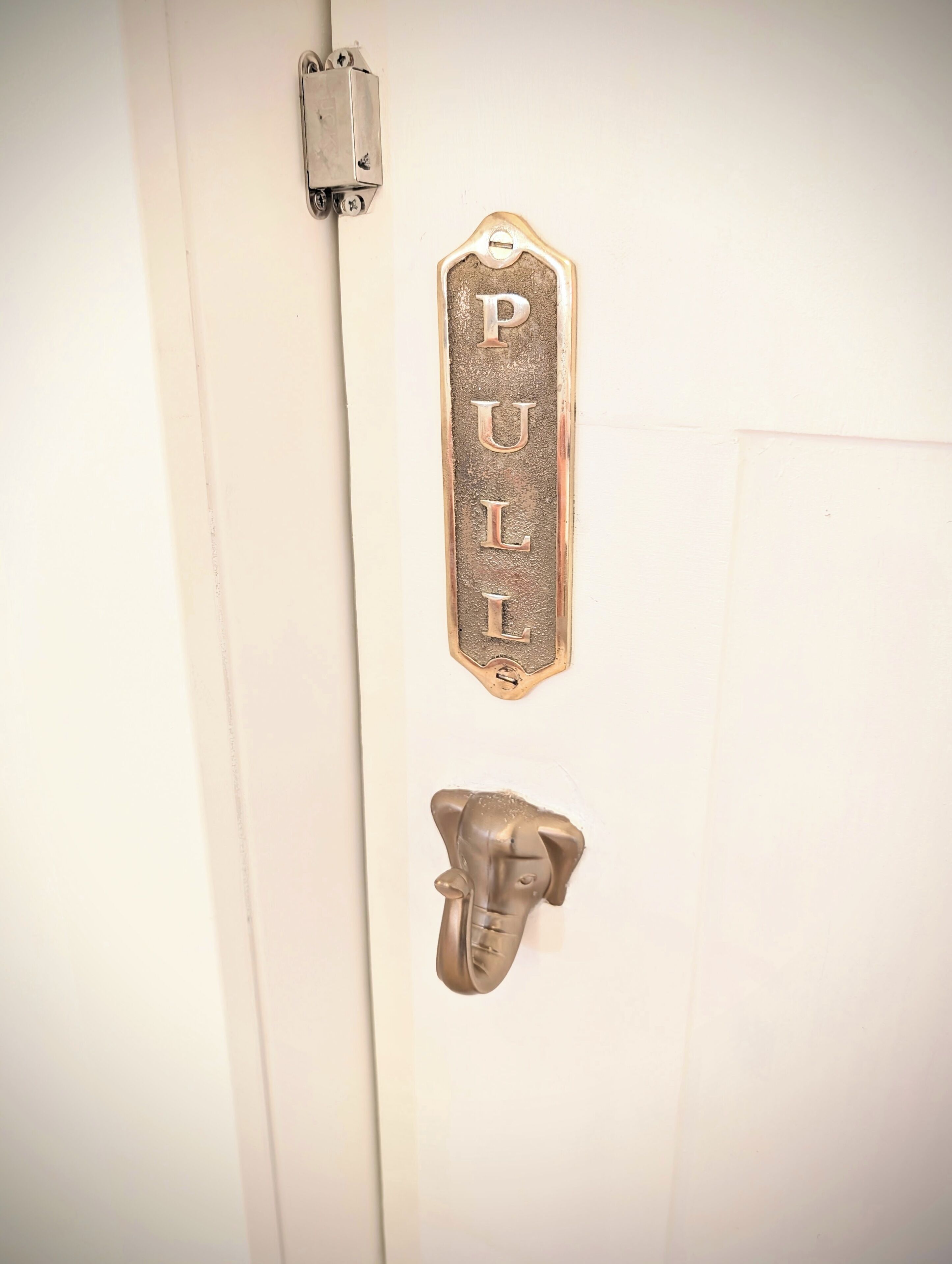 En dør med et træk håndtag og en metalplade med ordet 'PULL' præget på.