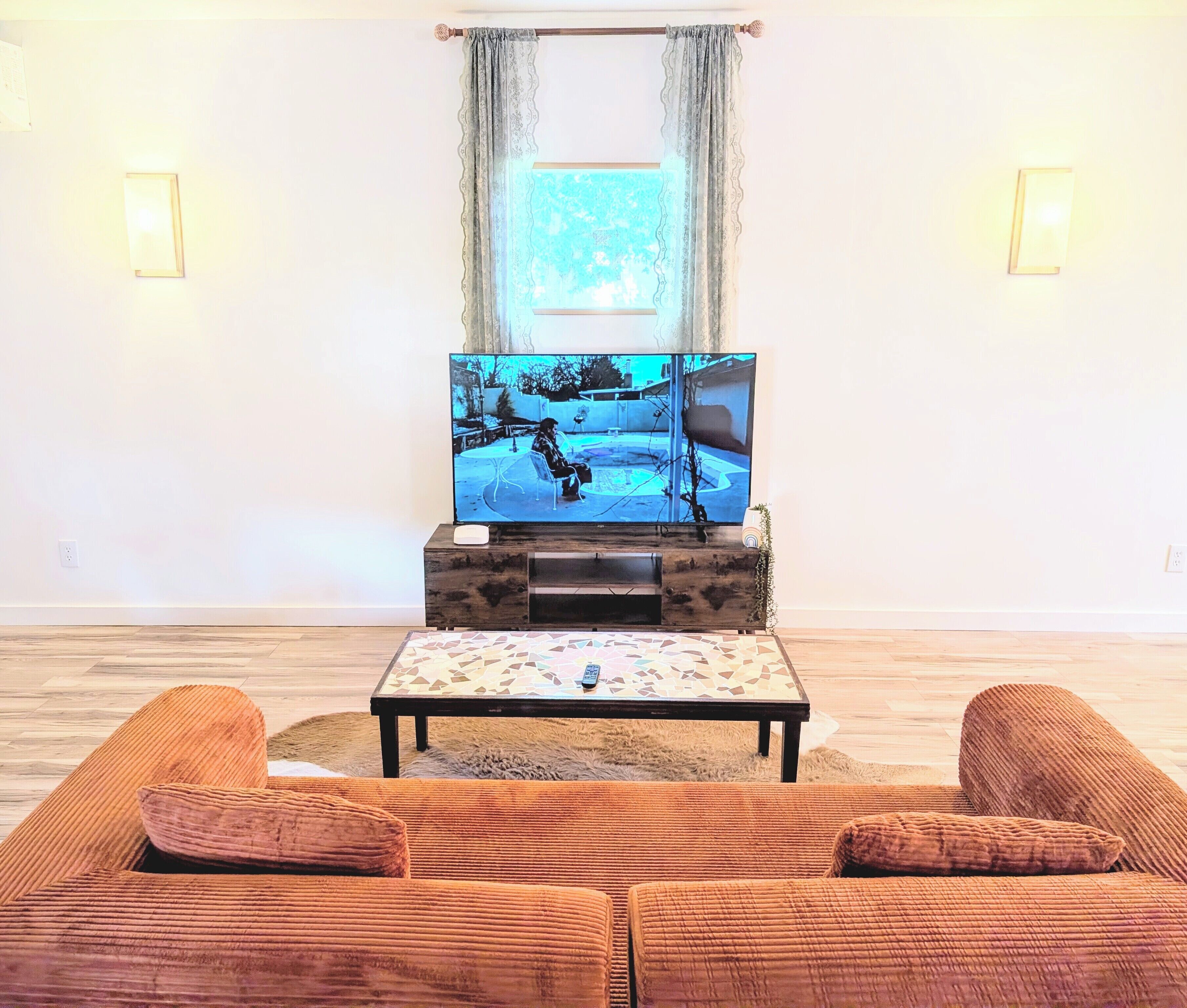 A living room with a television on a wooden stand, a small table, and a sofa.