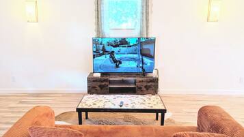 A living room with a television on a wooden stand, a small table, and a sofa.