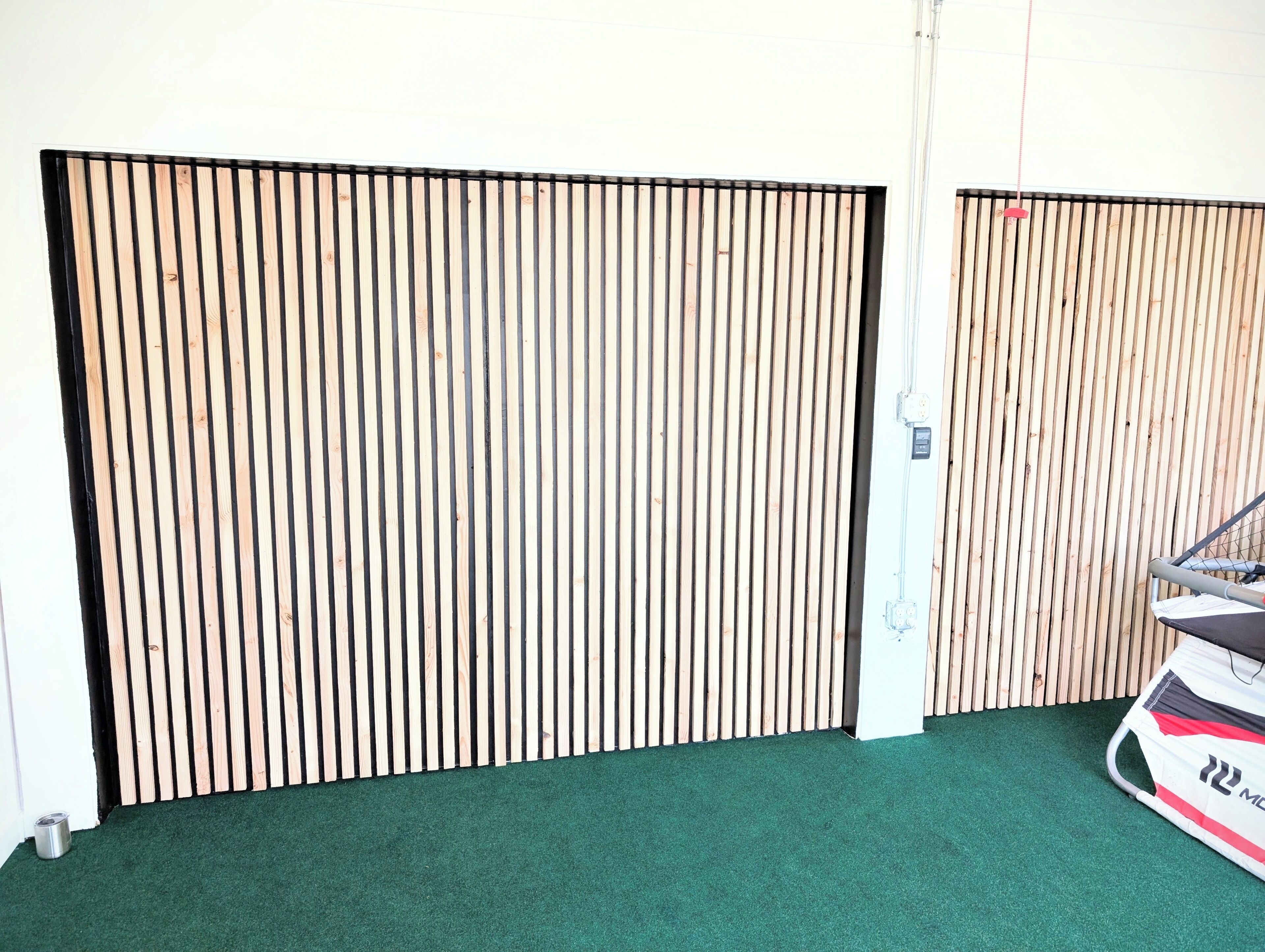 A room with a green carpet, a sliding door with vertical wooden slats, and a white wall.