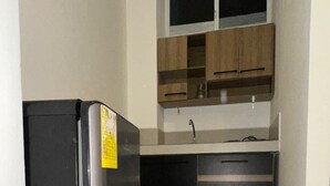 Uma cozinha compacta com geladeira, armários e uma janela sobre a pia.