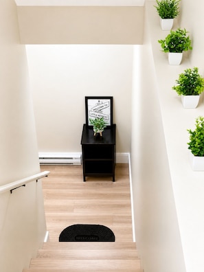 A staircase with a black console table, a welcome sign, and potted plants.
