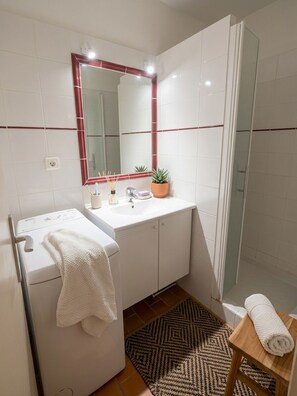 Ein modernes Badezimmer mit einem weißen Waschbecken, einem Spiegel und einer Duschkabine aus Glas.