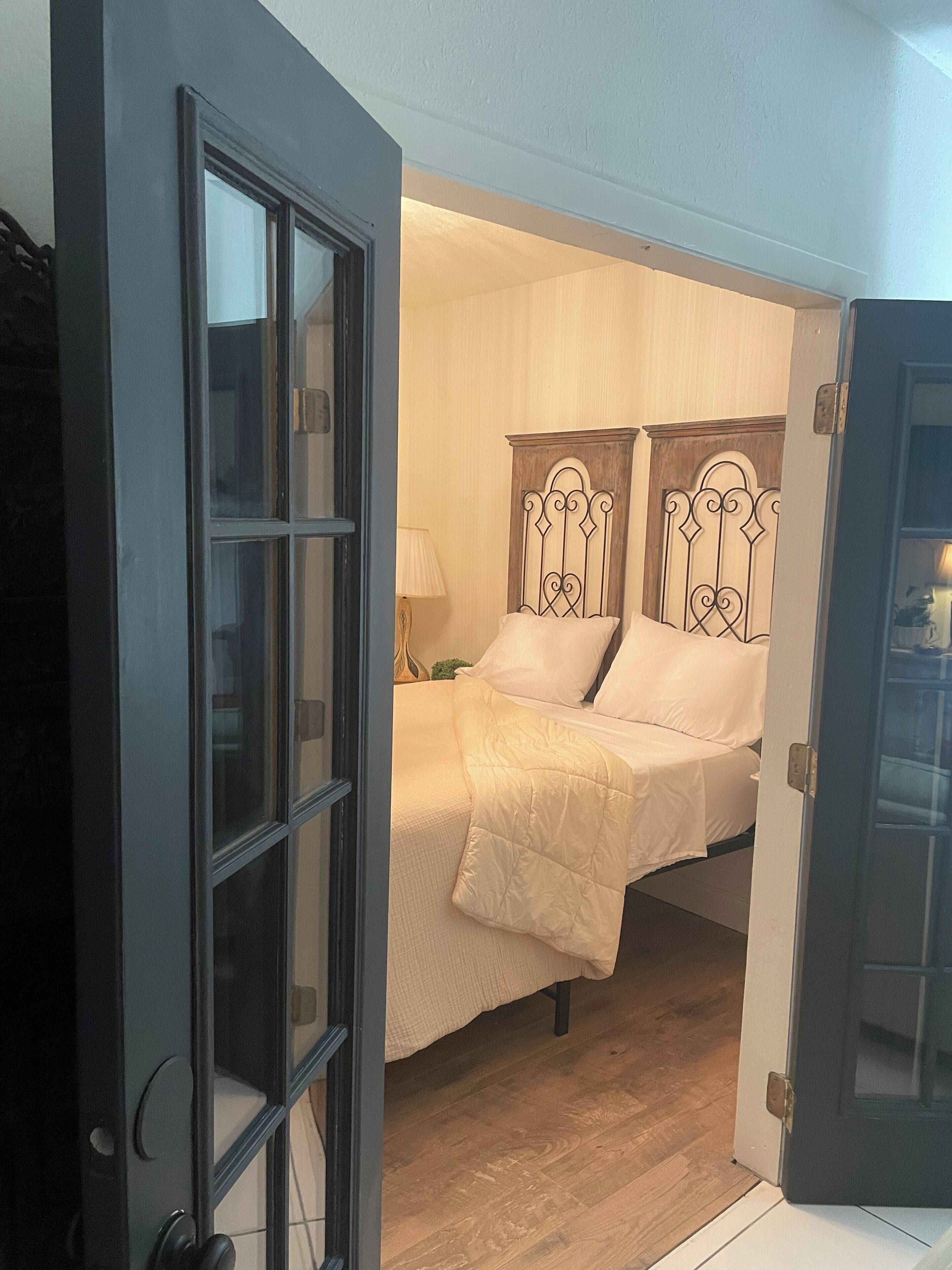 A room with a bed, a door, and a lamp.