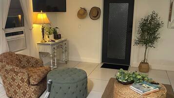 Un salon comprenant un canapé, un pouf et une petite table avec une lampe.