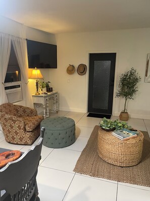 A living room with a sofa, ottoman, and a small table with a lamp. - Lovely “Dreamy Nook at Cocoa Village” (Cocoa)