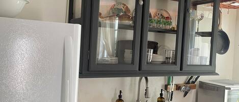 A kitchen with a white refrigerator, a sink, a toaster, and dark cabinets with glass doors.