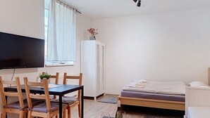 Ett rum med en säng, en tv, ett matbord med stolar och ett skåp.