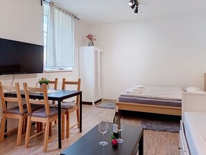 Ein Zimmer mit einem Bett, einem Fernseher, einem Esstisch mit Stühlen und einem Schrank.