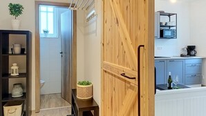 Ett modernt kök med mikrovågsugn, kaffebryggare och en vinflaska. Det finns en dörr av trä med ett handtag och ett litet bord med en växt.