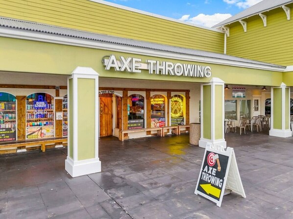 Área externa com uma placa indicando 'AXE THROWING' e uma seta de direção.