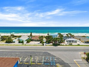 Eine Küstenstraße mit Parkplatz, Stoppschild und Gebäuden mit Blick auf den Strand.