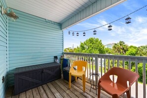 A covered porch with a bench, two chairs, and a string of lanterns. - Steps To Beach Access 45 & Salty Goat Saloon (Panama City Beach)