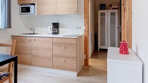 Una cucina compatta con mobili in legno, un forno a microonde, una macchina da caffè e un piccolo frigorifero.