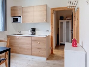 A compact kitchen with wooden cabinets, a microwave, a coffee maker, and a small refrigerator. - Apartment V&D 4 by Interhome (Rokytnice nad Jizerou)