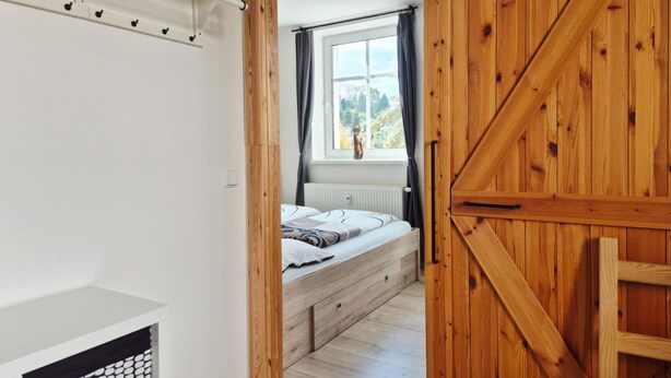 Una camera da letto con un letto, una finestra con tende, un termosifone e un armadio in legno.