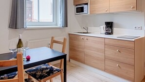 Una cucina compatta con mobili in legno, un forno a microonde, una moka e un tavolo con sedie.