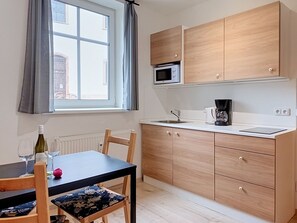 A compact kitchen with wooden cabinets, a microwave, a coffee maker, and a dining table with chairs. - Apartment V&D 4 by Interhome (Rokytnice nad Jizerou)