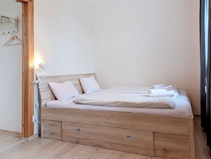 Ein Einzelbett mit Holz Kopfteil, ein Nachttisch und eine Pendelleuchte.
