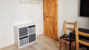 Una stanza con una porta scorrevole in stile cascina, un armadietto bianco con contenitori decorati, una sedia in legno e un televisore a parete.