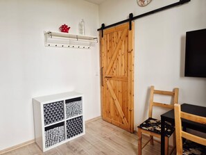 A room with a sliding barn-style door, a white cabinet with patterned storage, a wooden chair, and a mounted television. - Apartment V&D 4 by Interhome (Rokytnice nad Jizerou)