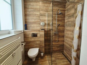 Un baño moderno con ducha, inodoro y ventana.