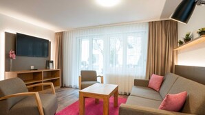 Una sala de estar moderna con sofá, sillones, una mesa de centro y televisor.