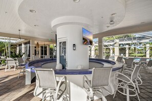 A poolside bar area with a circular seating arrangement and a view of the pool.