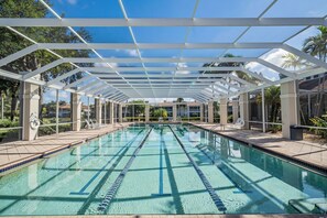 A clear swimming pool with a white canopy overhead, surrounded by lounge chairs and palm trees. - Newly Remodeled Naples Retreat - Resort-Style Living at Bridgewater Bay (Naples)
