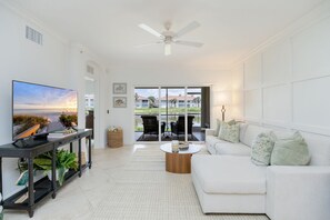 A modern living room with a flat-screen TV, a white sofa, and a coffee table. - Newly Remodeled Naples Retreat - Resort-Style Living at Bridgewater Bay (Naples)