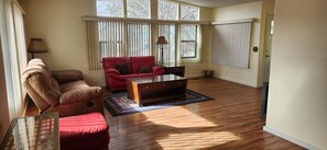A living room with a brown leather sofa, a red leather sofa, a wooden coffee table, and a patterned rug. - Fly in and stay! (Rimrock)