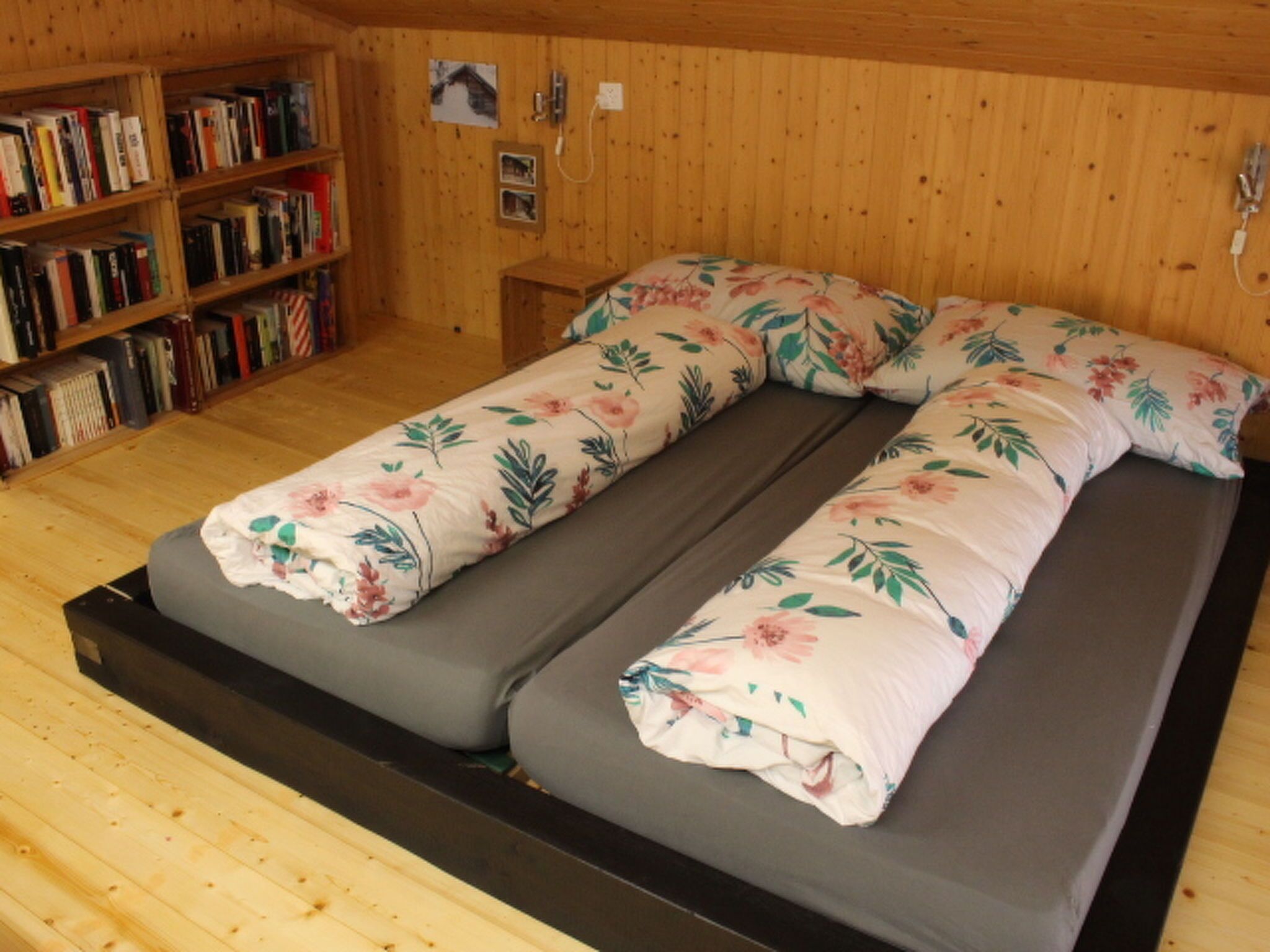 Una habitación con cama, una estantería y una pared de madera.
