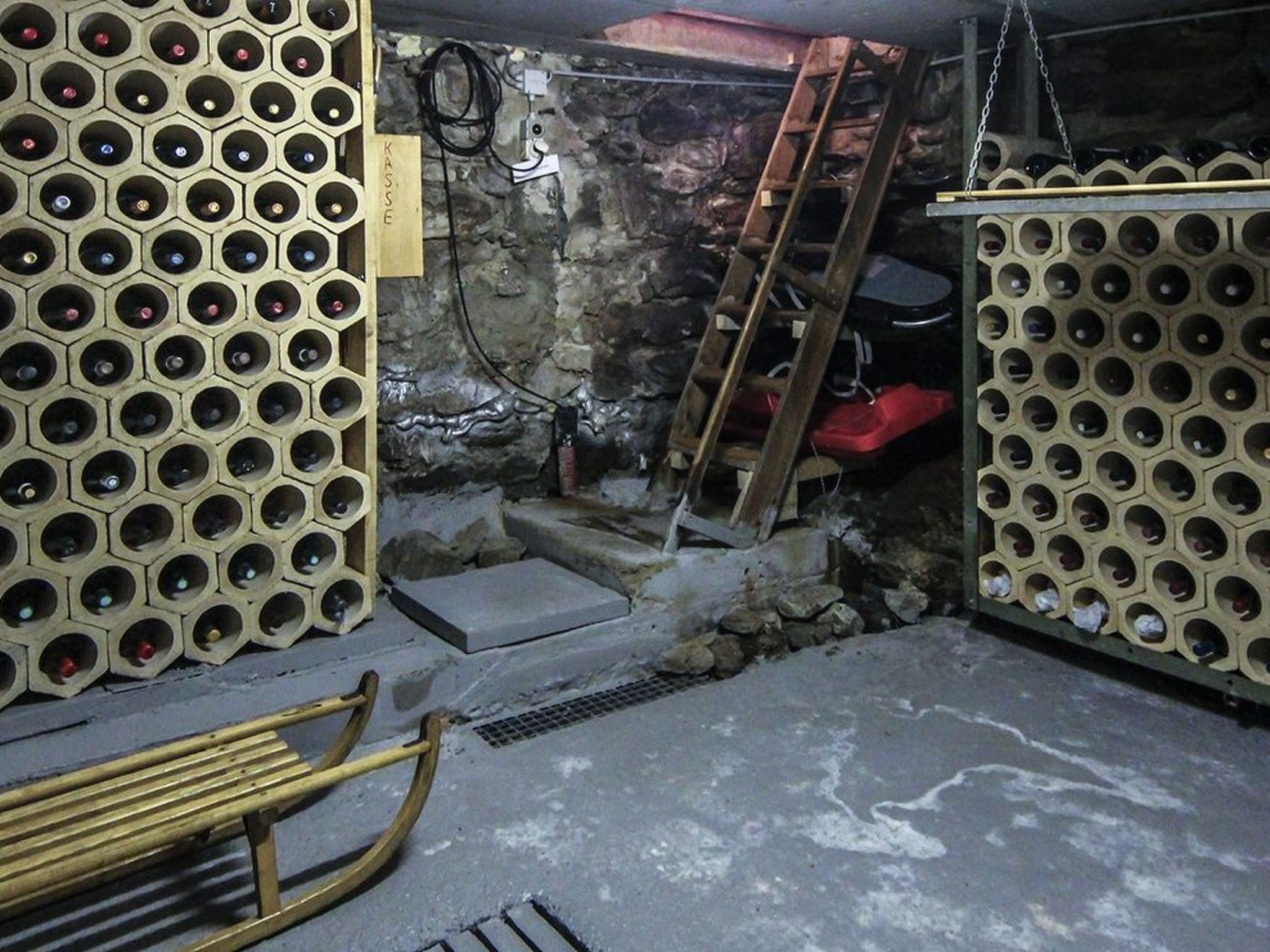Una habitación con paredes de diseño hexagonal, una escalera de madera y una rejilla metálica en el suelo.