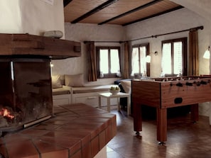 A cozy room with a fireplace, a sofa, a table, and a foosball table. - Gabrielenhaus, (Wassen UR), by Interhome (Wassen UR)