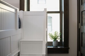 A white bench with a potted plant beside a window.