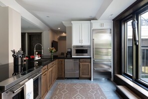 A modern kitchen with stainless steel appliances, wooden cabinets, and a large window.