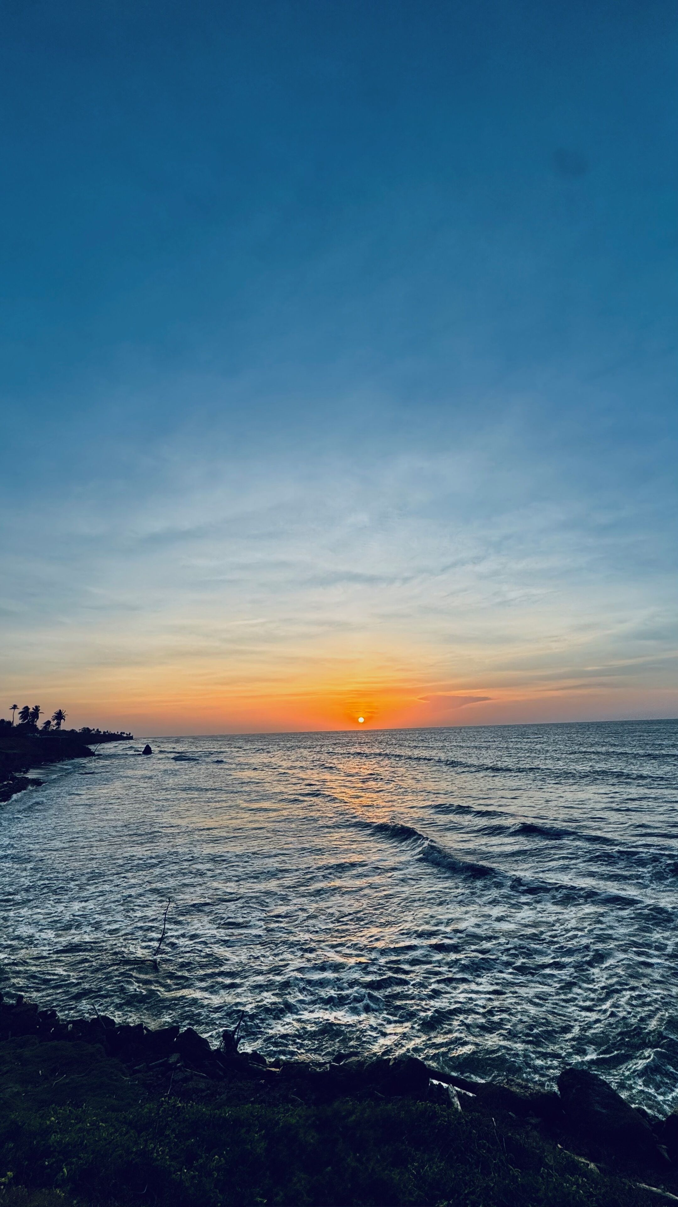 A coastal sunset with waves and a clear sky.