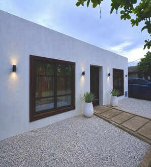 A modern building with large windows, a gravel driveway, and potted plants. - Maré House | House for 10 people with air conditioning | 50 m from the sea (Arboletes)