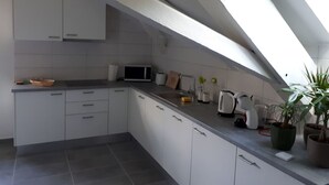 A modern kitchen with white cabinets, a microwave, a kettle, and a sink. - Les Gîtes du Gore Virat, (Corcelles BE), by Interhome (Corcelles)