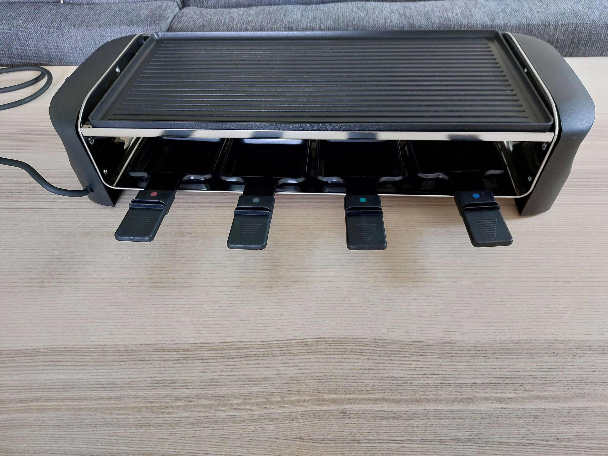 Un radiateur portatif noir, doté de quatre boutons de commande, posé sur une surface en bois.