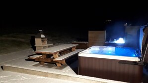Een buitenzwembad met houten bank en barbecue.