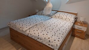 Een slaapkamer met een bed, nachtkastje, lamp en een raam met jaloezieën.