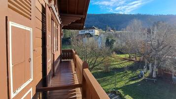 Un balcon en bois offrant une vue sur un paysage rural, avec des maisons et des arbres.