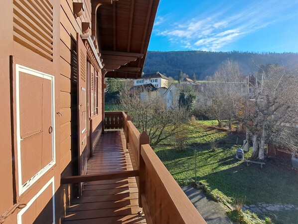 Ein Holzbalkon mit Blick auf eine ländliche Landschaft, darunter Häuser und Bäume.