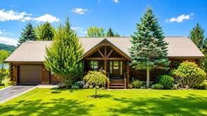 A log cabin with a front porch, a garage, and a well-maintained lawn.