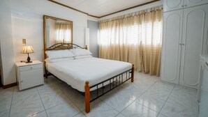 A bedroom with a bed, nightstand, lamp, mirror, wardrobe, and curtains. - Watson Residence w/Private pool, Billiards, and Tennis Court (Central Visayas)