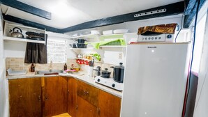 A compact kitchen with wooden cabinets, a white refrigerator, and a stove. - Watson Residence w/Private pool, Billiards, and Tennis Court (Central Visayas)